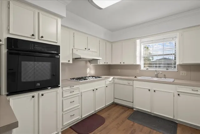 a kitchen with granite countertop white cabinets and white appliances