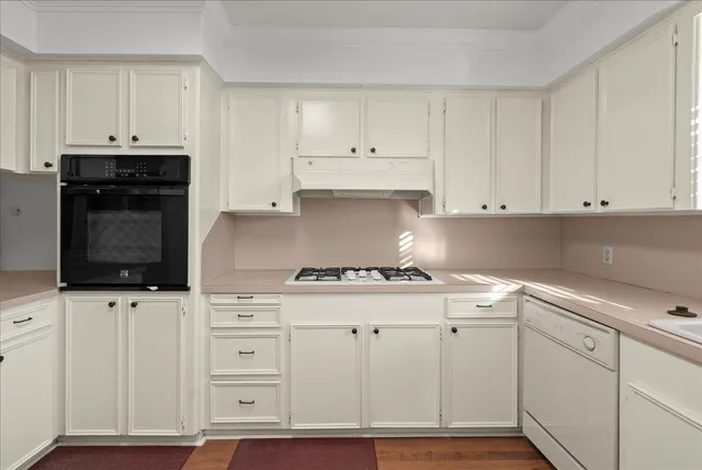 a kitchen with white cabinets and appliances