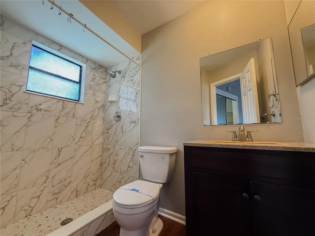 5364 Deltona Boulevard Spring Hill, FL 34606 - Photo 22 of 36 a bathroom with a granite countertop toilet sink and mirror