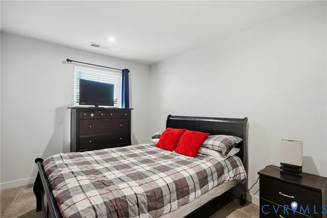 a bedroom with a bed and a flat tv screen on a dresser