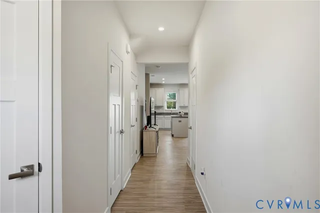 a view of a hallway with wooden floor and a bathroom