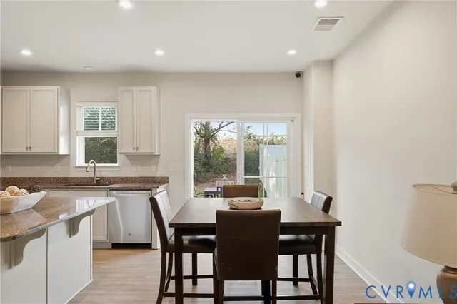 a kitchen with a dining table chairs and white cabinets