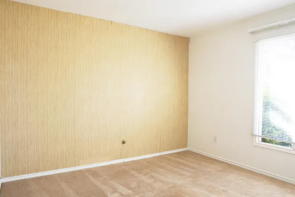 an empty room with a window and a fan