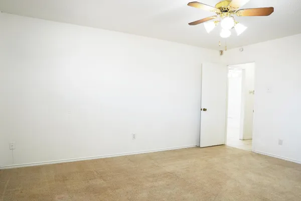 an empty room with wooden floor chandelier and windows