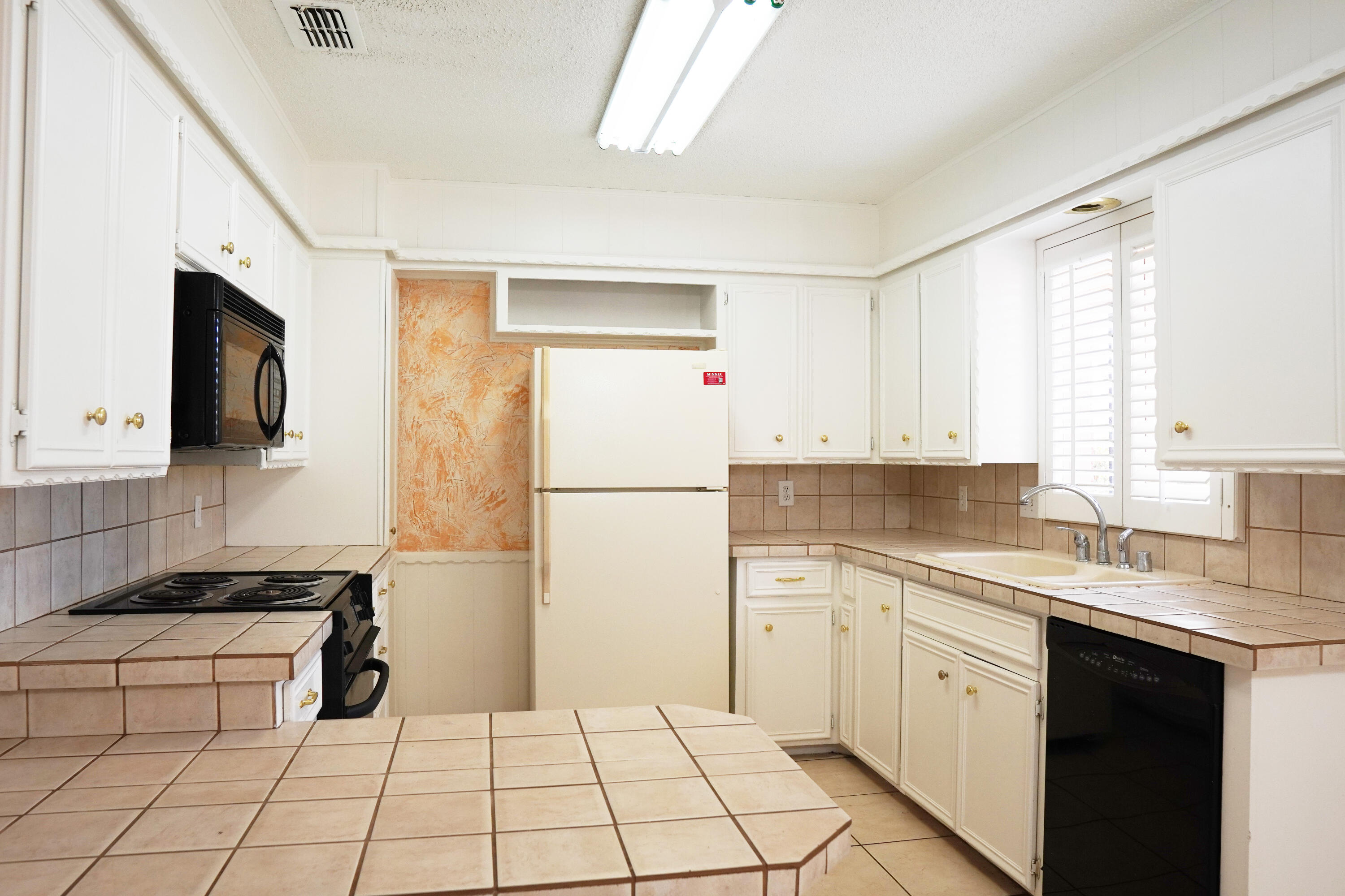 5520 80th Street Lubbock, TX 79424 - Photo 7 of 29 a kitchen with a sink a stove top oven a refrigerator and white cabinets