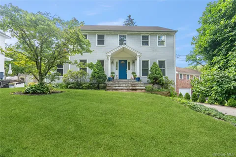 a front view of a house with a yard and trees