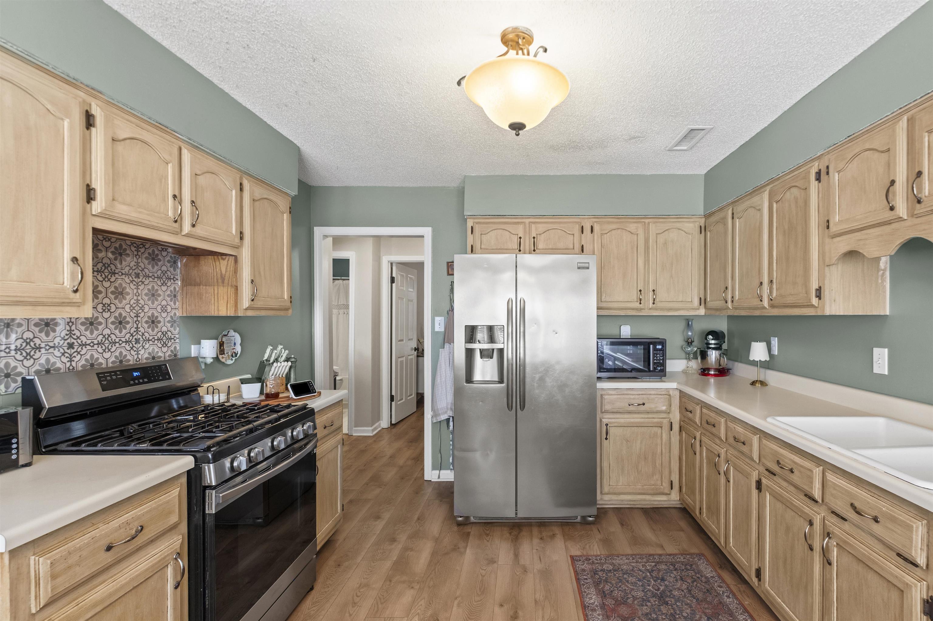 3601 Marshall Road Munford, TN 38058 - Photo 19 of 35 Kitchen featuring wood-finish cabinetry, solid surface countertops, a stainless steel range, and a patterned tile backsplash