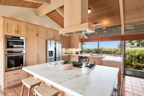 a kitchen with stainless steel appliances kitchen island granite countertop a refrigerator a sink dishwasher a stove and white cabinets with wooden floor