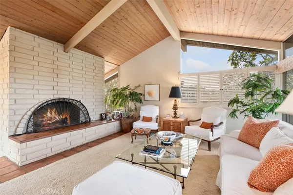 a living room with furniture a fireplace and a dining table with floor to ceiling window