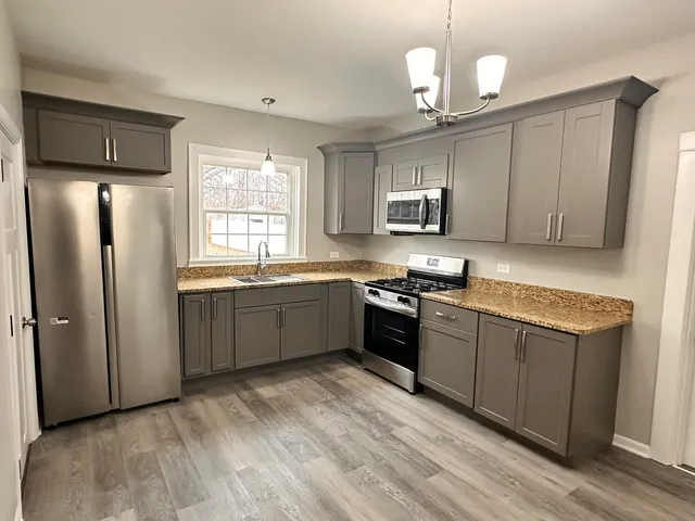 a kitchen with stainless steel appliances granite countertop a stove a sink dishwasher a refrigerator and a microwave oven with wooden floor