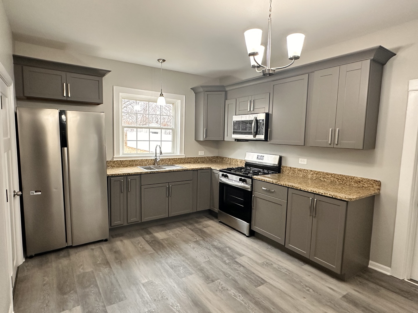 920 Hall Street Streator, IL 61364 - Photo 5 of 19 a kitchen with stainless steel appliances granite countertop a stove a sink dishwasher a refrigerator and a microwave oven with wooden floor