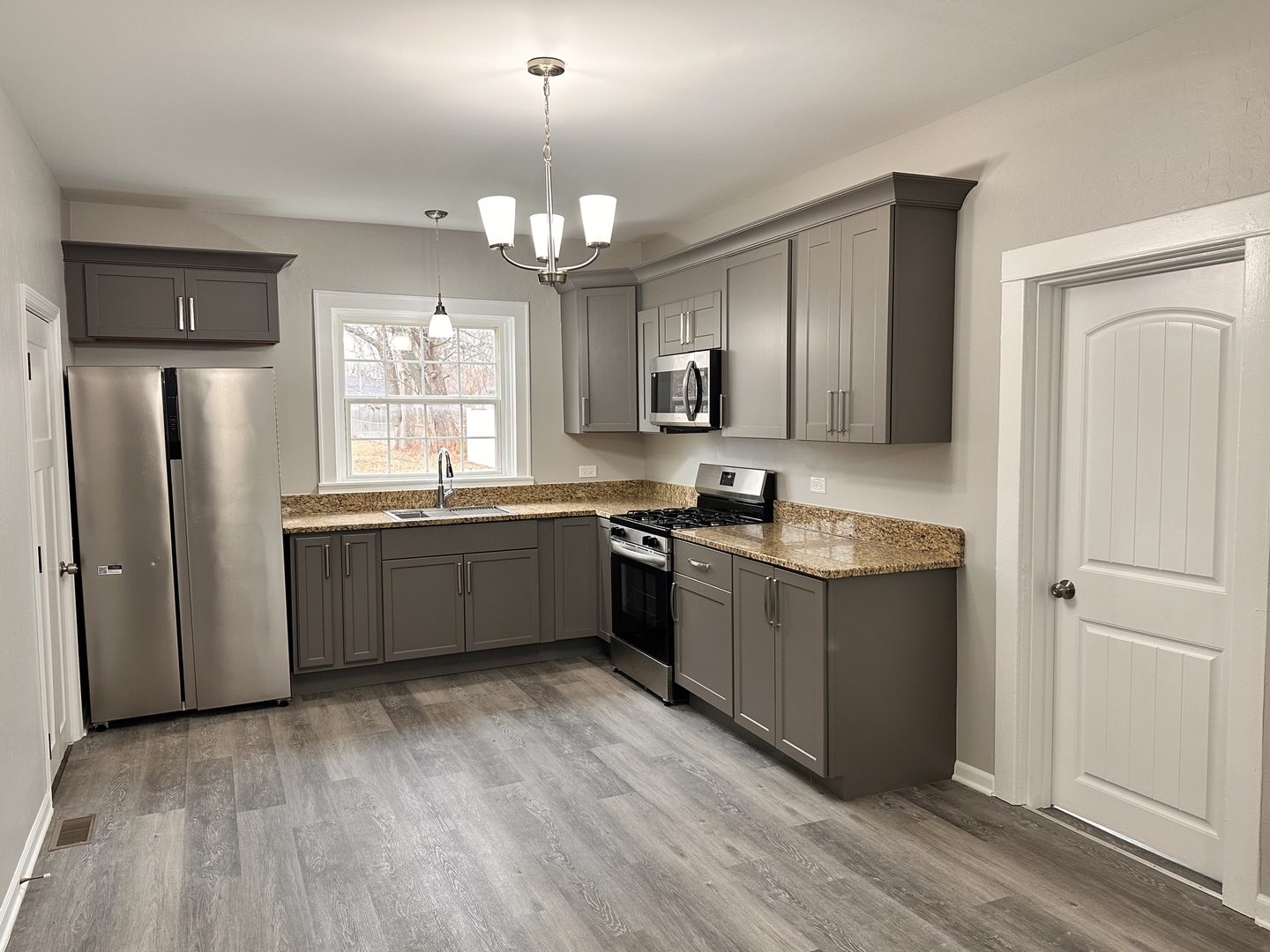 920 Hall Street Streator, IL 61364 - Photo 6 of 19 a large kitchen with stainless steel appliances granite countertop a refrigerator a sink dishwasher a stove with wooden floors and cabinets