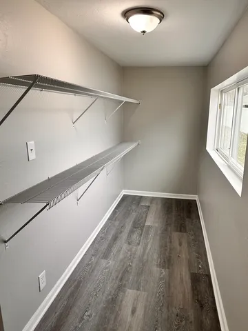 a view of a room with wooden floor and small window