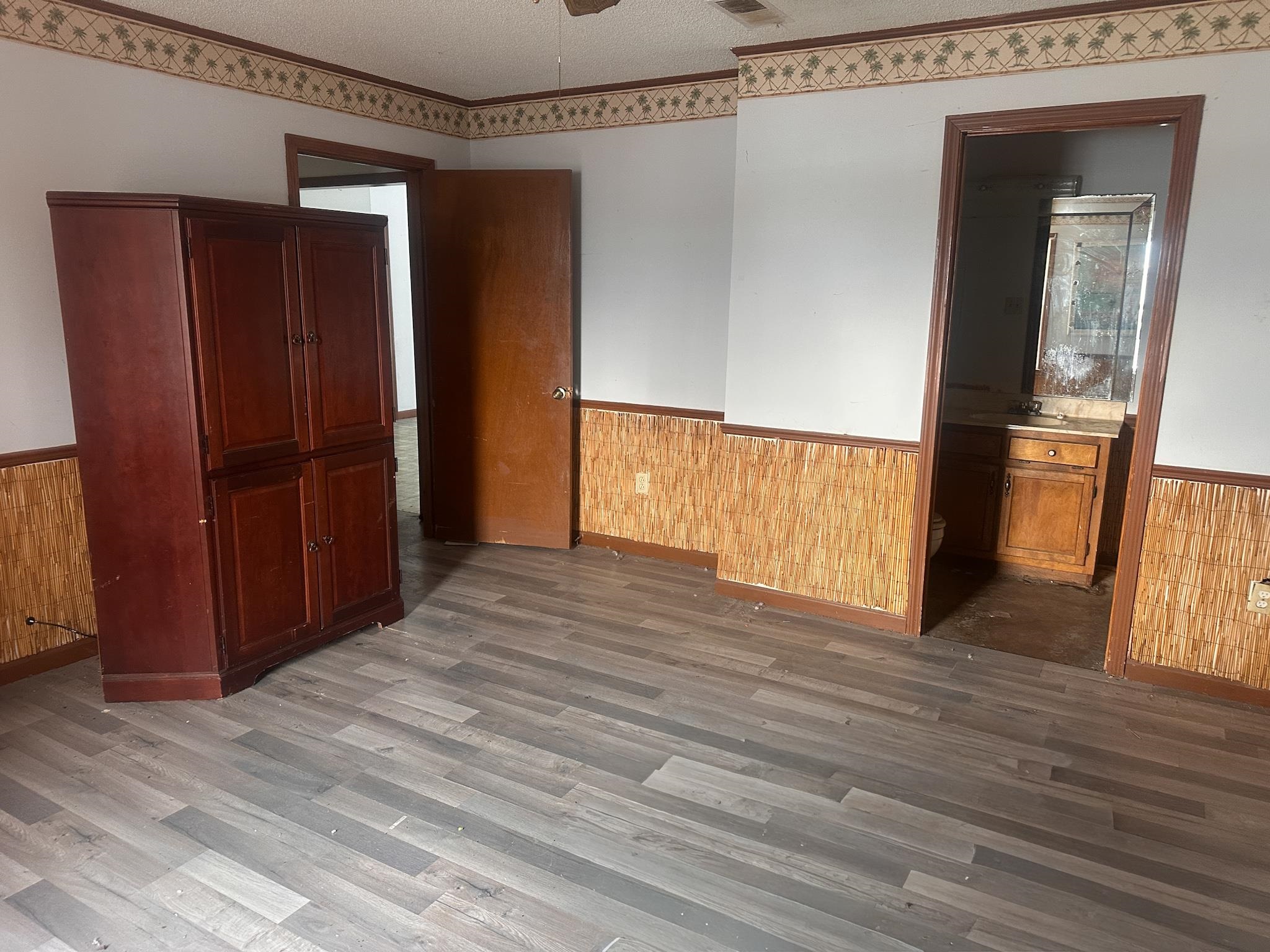 605 Jr Drive Covington, TN 38019 - Photo 11 of 21 Unfurnished room with wainscoting, wood walls, a ceiling fan, dark wood-type flooring, and a textured ceiling