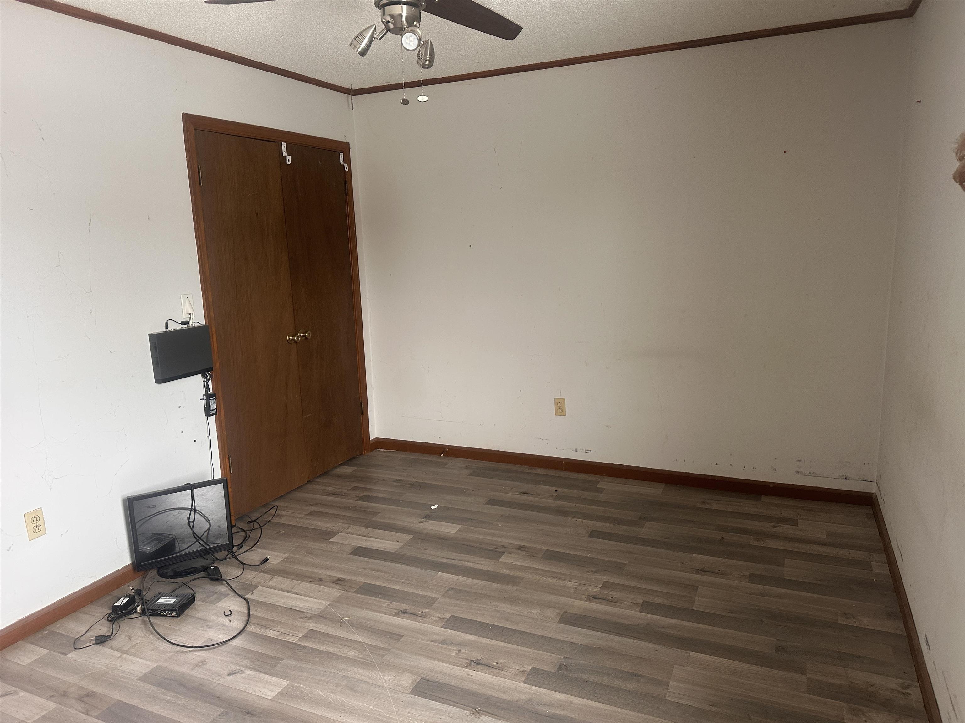 605 Jr Drive Covington, TN 38019 - Photo 18 of 21 Empty room featuring crown molding, ceiling fan, wood finished floors, and a textured ceiling