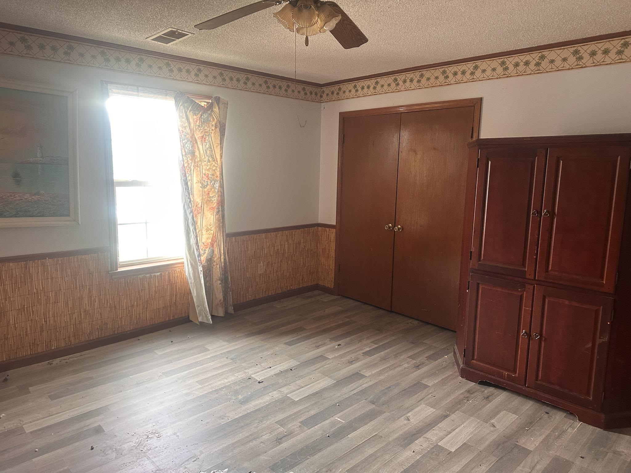 605 Jr Drive Covington, TN 38019 - Photo 10 of 21 Unfurnished bedroom featuring a wainscoted wall, a textured ceiling, a closet, wood walls, and ceiling fan
