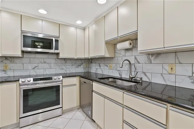 a kitchen with white cabinets stainless steel appliances and a sink