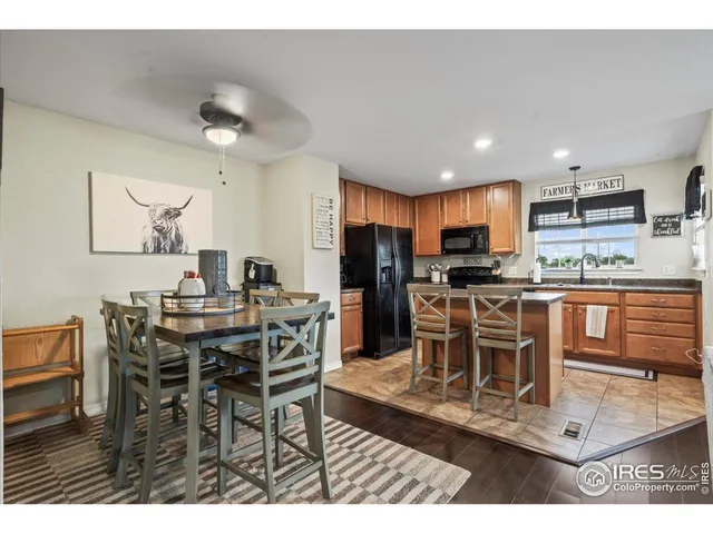 a kitchen with stainless steel appliances kitchen island granite countertop a dining table chairs and a refrigerator