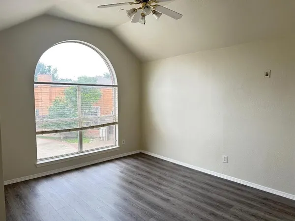 an empty room with wooden floor a ceiling fan and windows