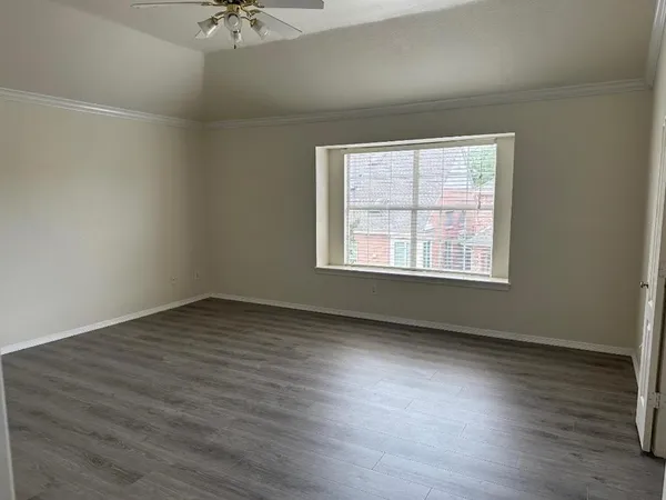 an empty room with wooden floor chandelier fan and windows