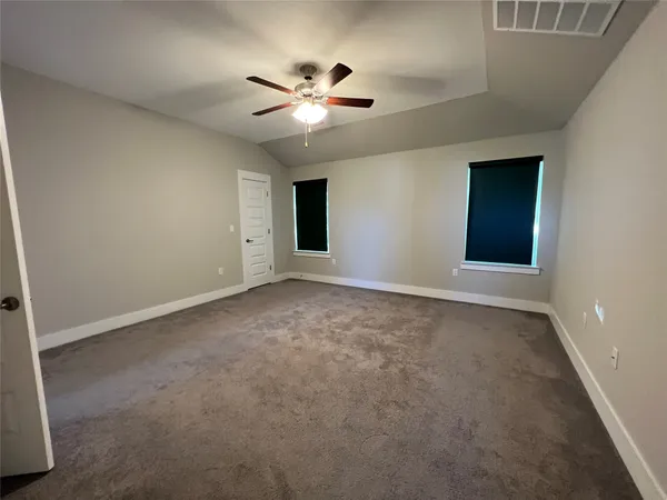 an empty room with chandelier fan and windows