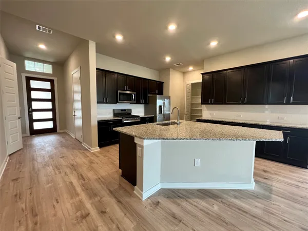 a living room with stainless steel appliances furniture a flat screen tv and view kitchen