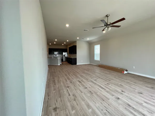 a view of a livingroom with a ceiling fan wooden floor and window