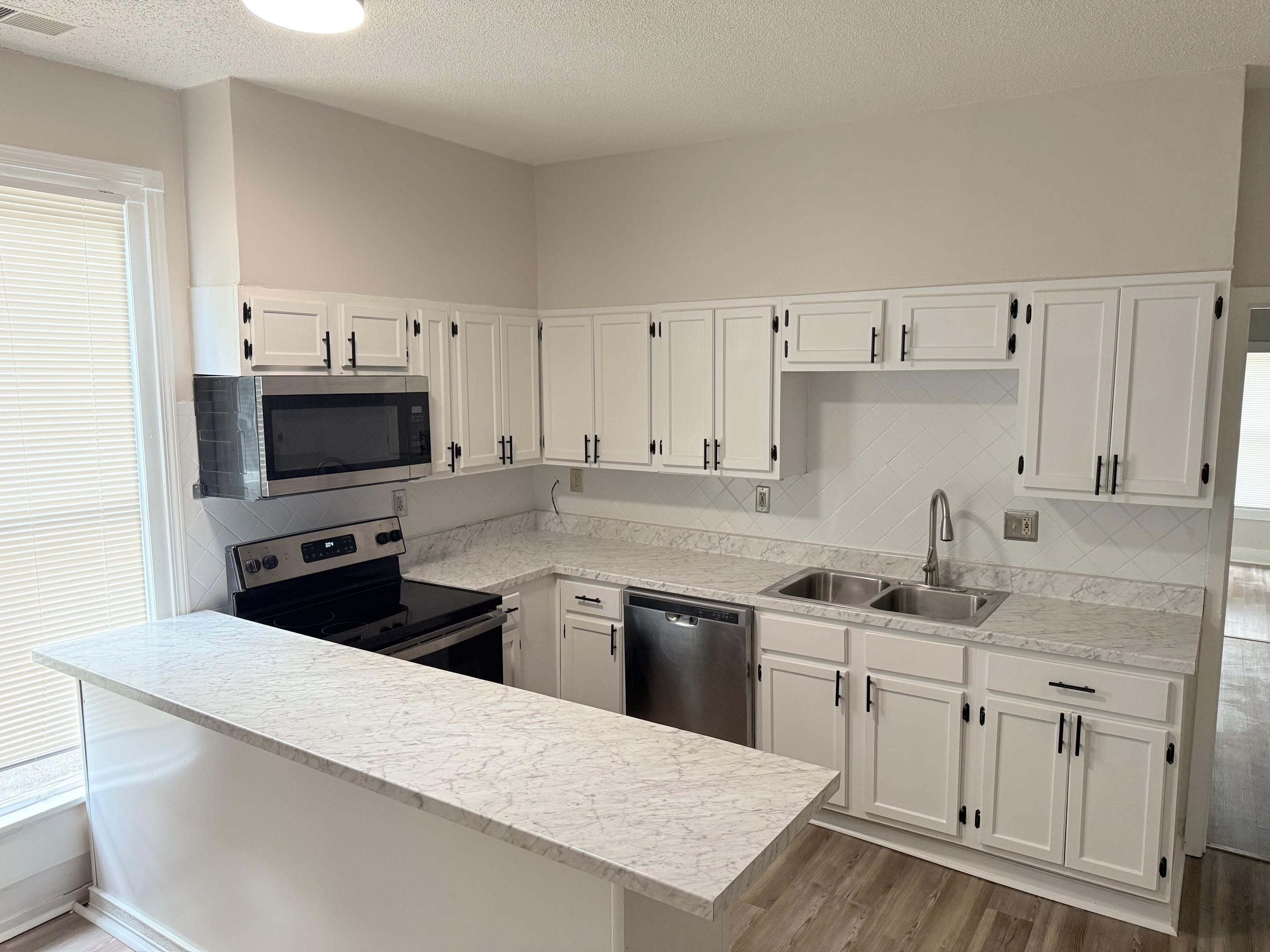 5657 Raleigh Lagrange Road Memphis, TN 38134 - Photo 6 of 8 Kitchen featuring appliances with stainless steel finishes, a sink, dark wood finished floors, white cabinets, and a textured ceiling