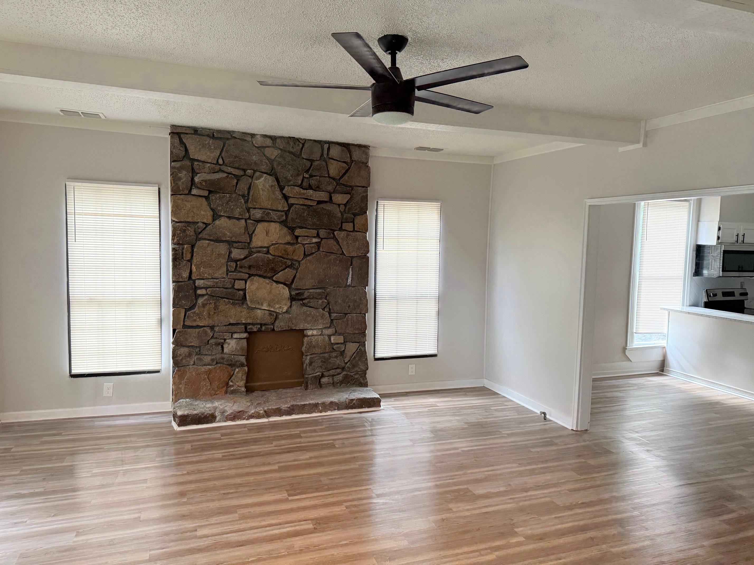 5657 Raleigh Lagrange Road Memphis, TN 38134 - Photo 8 of 8 Unfurnished living room with a textured ceiling, plenty of natural light, light wood-style floors, baseboards, and a ceiling fan