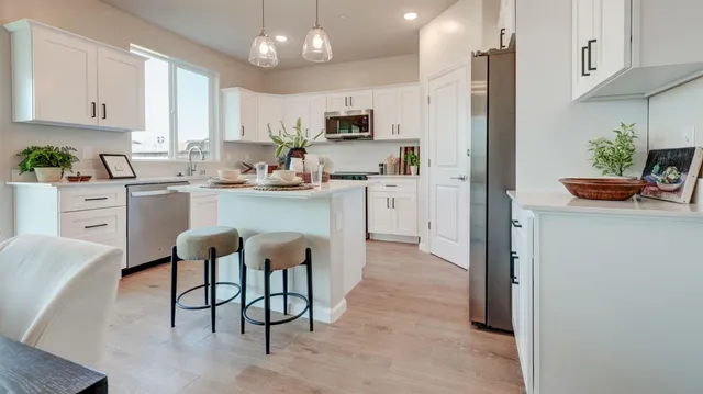 a kitchen with stainless steel appliances granite countertop a refrigerator a stove a sink a dining table and chairs with wooden floor