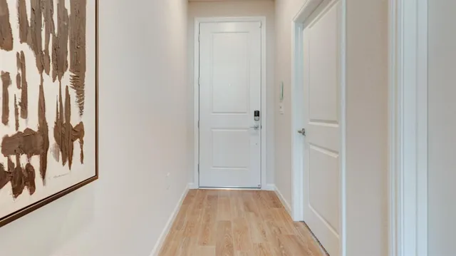 a view of a hallway with wooden floor and a bathroom