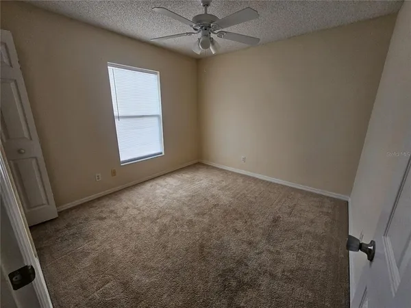 an empty room with windows and fan