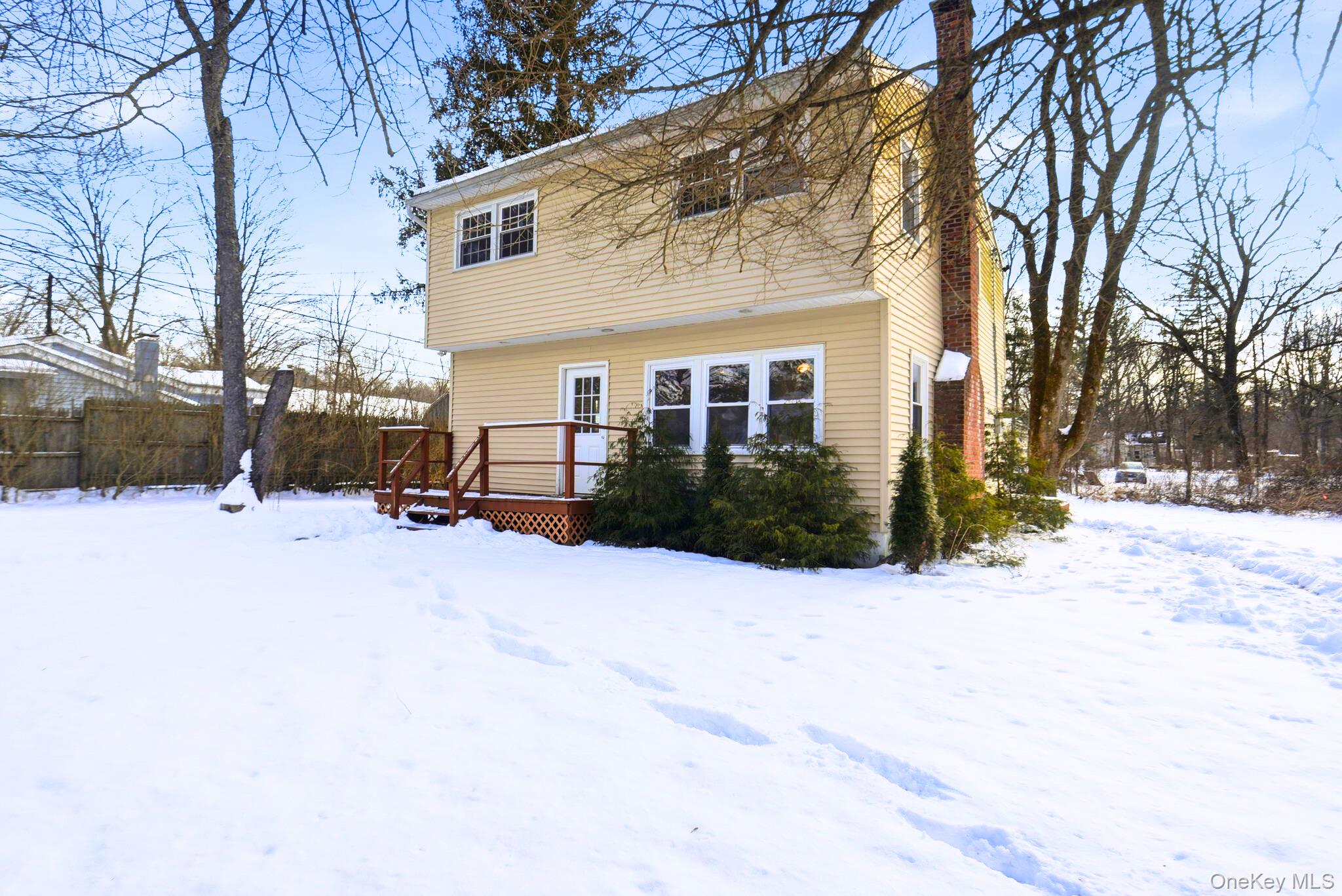 Snow covered property featuring a deck and a chimney