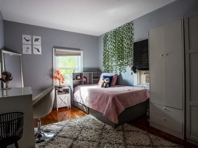 a bedroom with a bed a mirror on dresser and a window