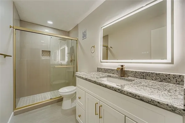 a bathroom with a granite countertop sink a mirror and a toilet