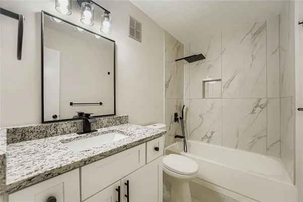 a bathroom with a granite countertop sink toilet and shower