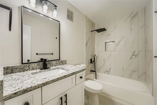 a bathroom with a granite countertop sink toilet and shower