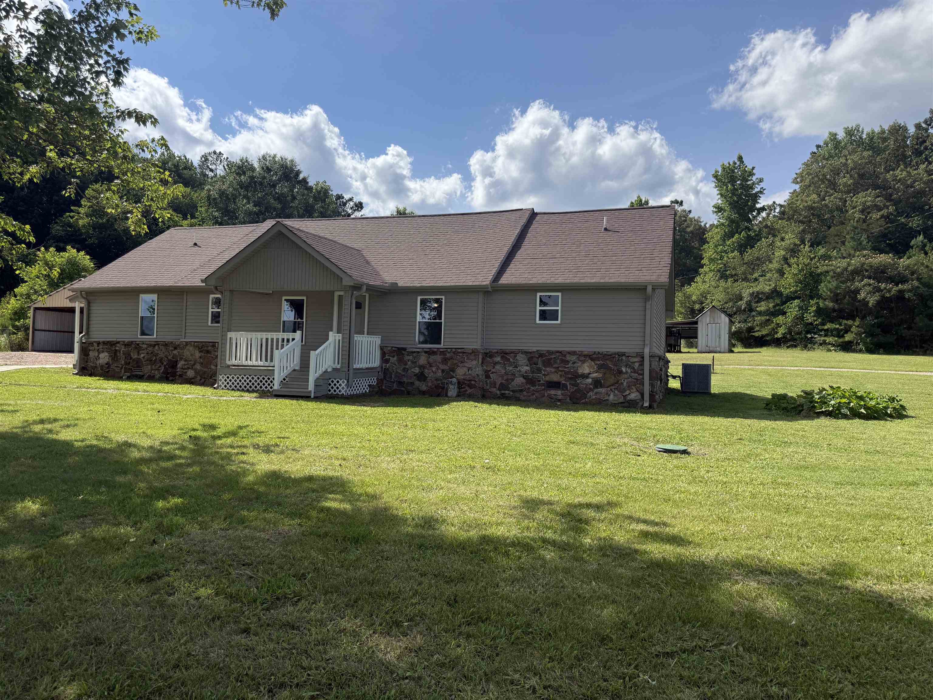 170 Leapwood Road Enville, TN 38332 - Photo 2 of 33 Ranch-style residence featuring a covered front porch, stone and siding exterior, asphalt shingle roof, and a gravel driveway leading to a detached carport