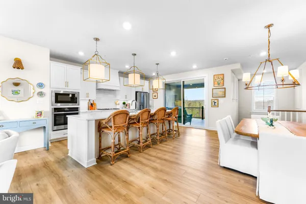 a kitchen with stainless steel appliances granite countertop a kitchen island a stove a dining table and chairs with wooden floor