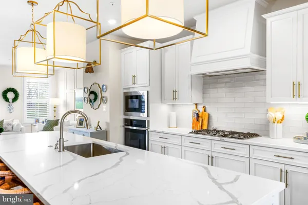 a kitchen with stainless steel appliances a refrigerator a sink dishwasher a stove and white cabinets with wooden floor