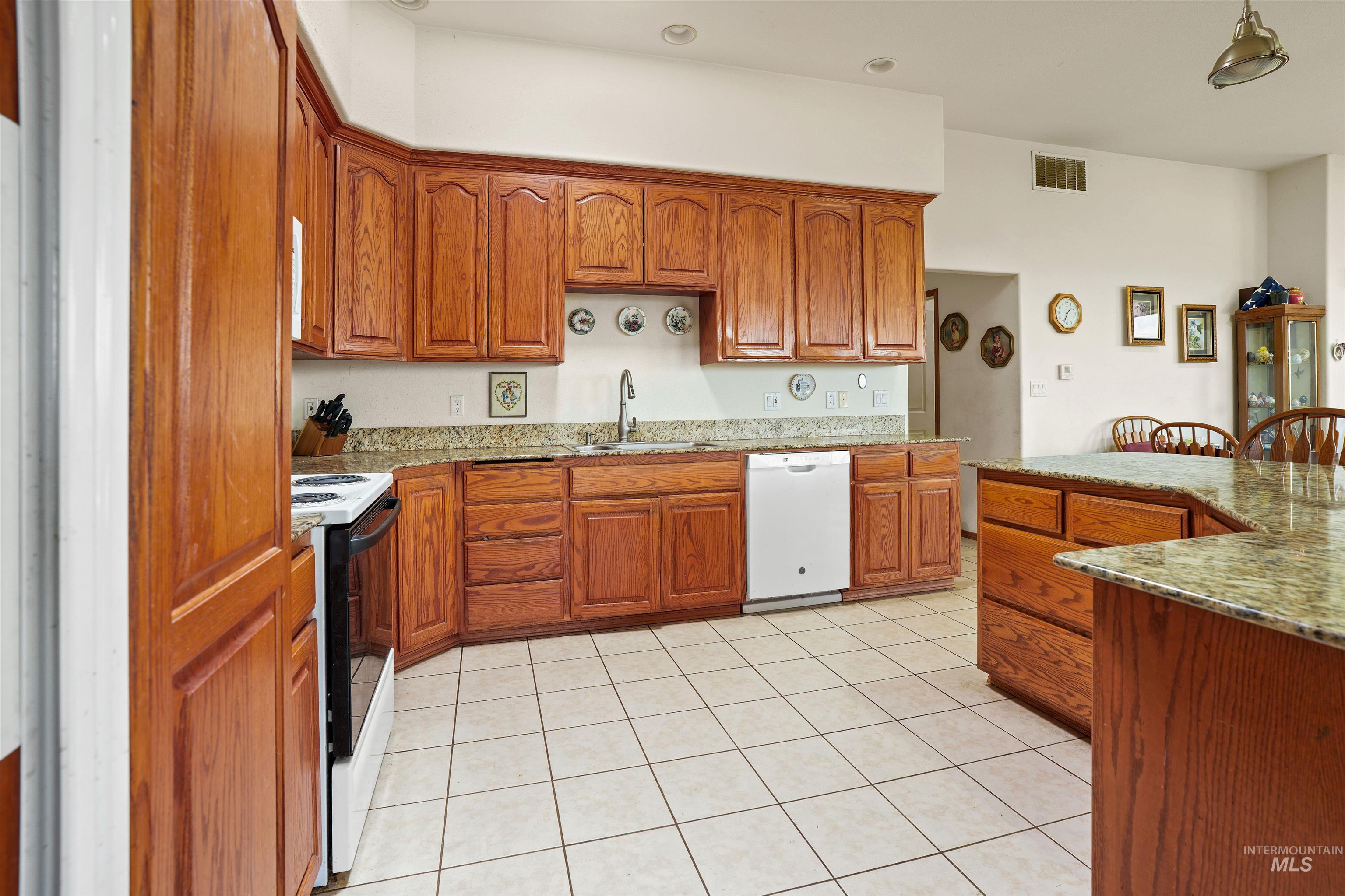 2750 South Perry Lane Clarkston, WA 99403 - Photo 19 of 47 Kitchen featuring wood cabinetry, light-toned granite countertops, a stainless steel sink with a single-handle faucet, and white tile flooring