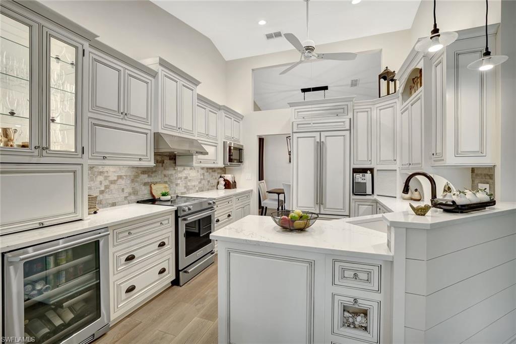 2540 Talon Court, Unit 504 Naples, FL 34105 - Photo 11 of 31 Kitchen with wine cooler, stainless steel appliances, light stone counters, a peninsula, and under cabinet range hood