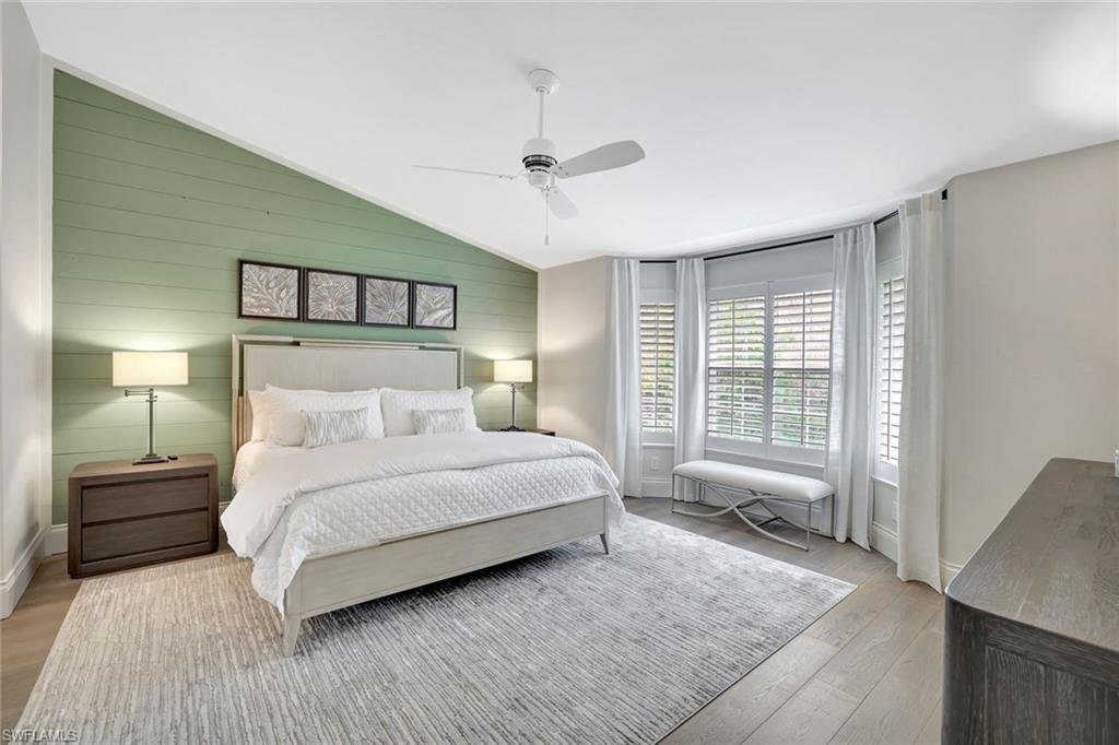 2540 Talon Court, Unit 504 Naples, FL 34105 - Photo 15 of 31 Bedroom featuring wood walls, vaulted ceiling, ceiling fan, and wood finished floors