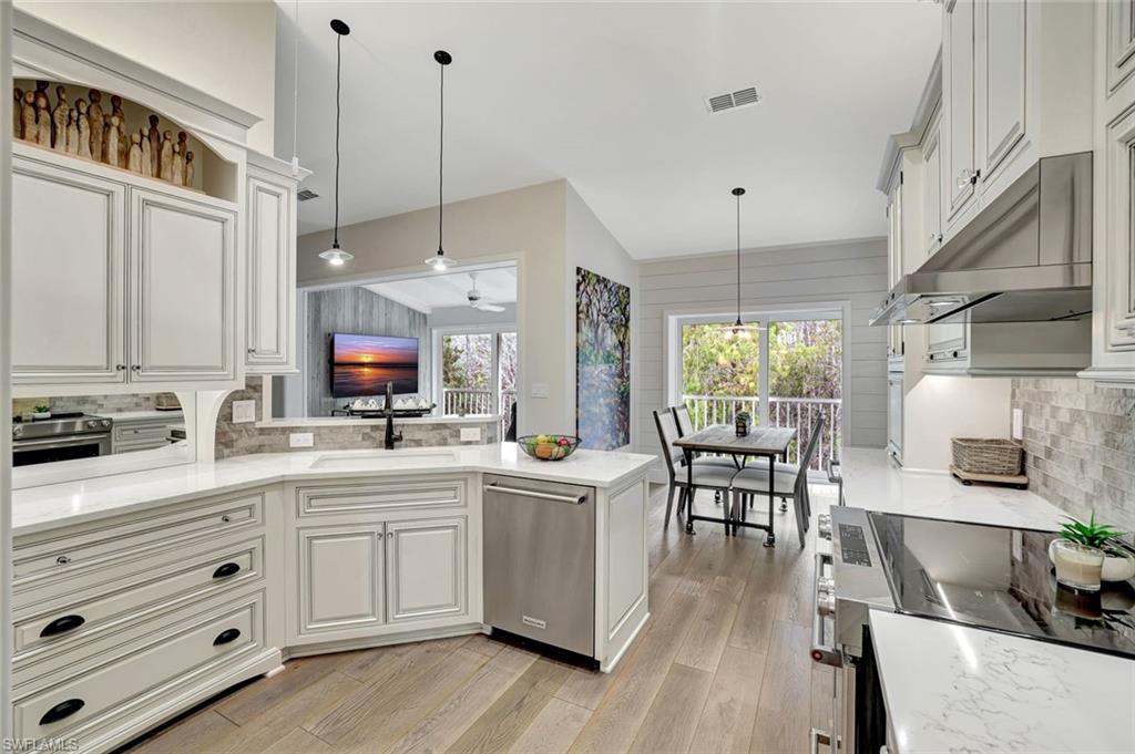 2540 Talon Court, Unit 504 Naples, FL 34105 - Photo 10 of 31 Kitchen with tasteful backsplash, appliances with stainless steel finishes, decorative light fixtures, and under cabinet range hood