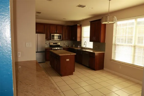 a kitchen with stainless steel appliances granite countertop a stove a sink a refrigerator and a cabinets