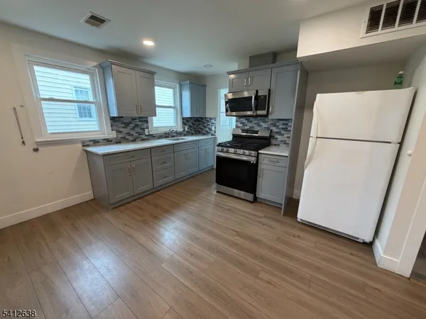 a kitchen with a refrigerator a stove top oven a sink and dishwasher with wooden floor