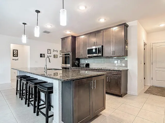 a kitchen with kitchen island granite countertop a sink a counter top space appliances and cabinets