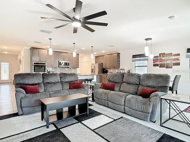 a living room with furniture kitchen view and a chandelier