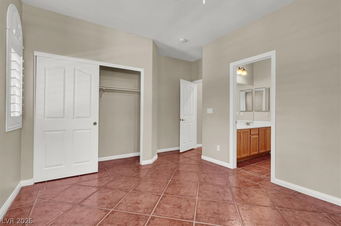 7308 Rustic Meadow Street Las Vegas, NV 89131 - Photo 12 of 27 Terracotta tile flooring extends from this adaptable bedroom into an adjoining private bath.