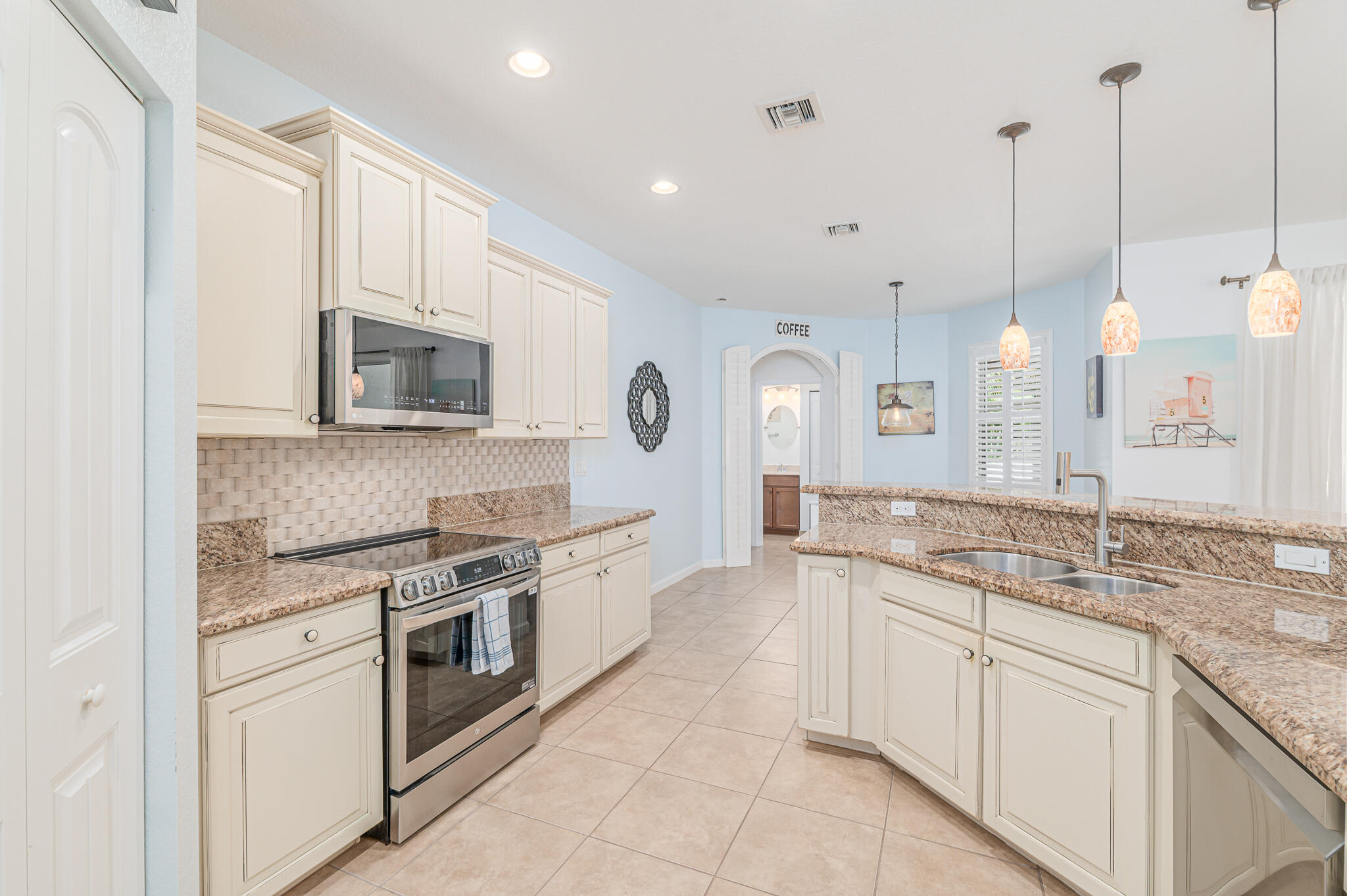 2187 Northwest Dalea Way Stuart, FL 34994 - Photo 18 of 41 a large white kitchen with stainless steel appliances granite countertop a stove a sink and a microwave